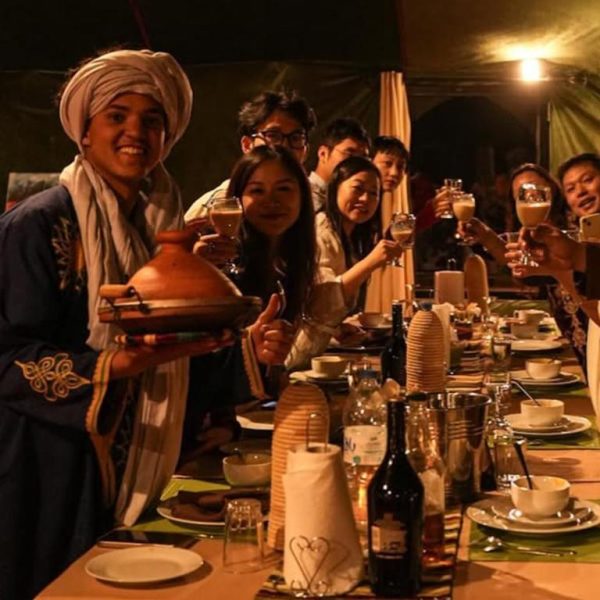 Cena tradicional marroquí con tajín en la jaima del Velaria Luxury Camp bajo luz cálida nocturna