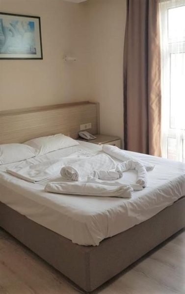 Habitación doble con cama matrimonial y toallas decoradas en Larsens Suit Hotel