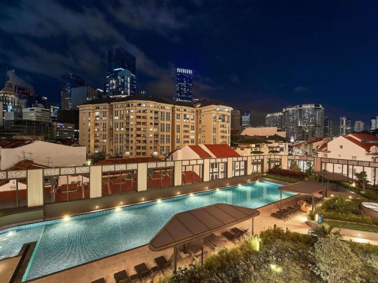 Piscina exterior iluminada de noche en el Mercure ICON Singapore City Centre con vistas al skyline
