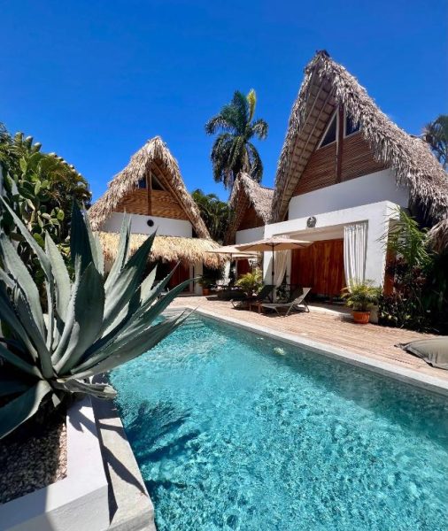 Piscina exterior con cabañas de techo de palma y terraza en Leeloo Boutique Hotel