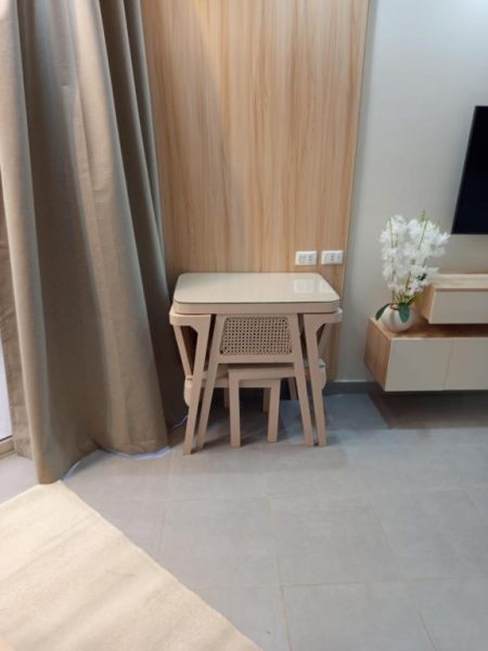 Escritorio de madera con silla rattan y taburete en habitación del Hotel y Resort Scandic