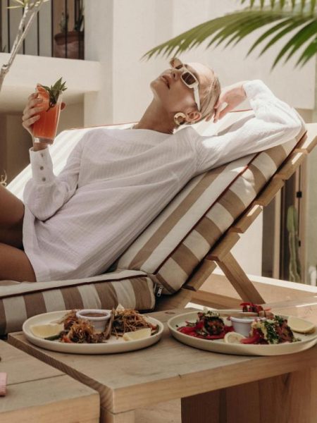 Mujer relajándose con cóctel en terraza del Hotel Panamera con platos gourmet