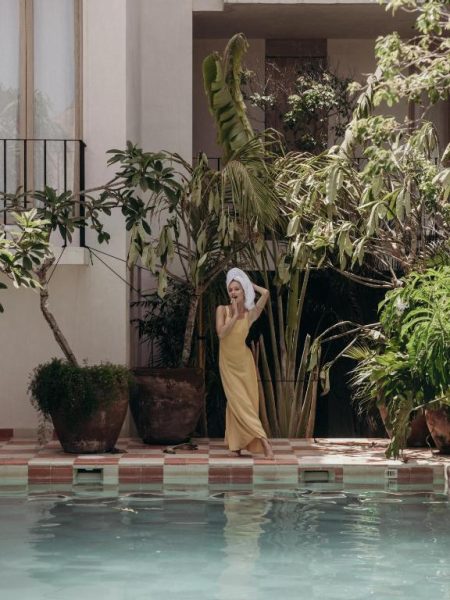 Mujer junto a la piscina rodeada de jardín tropical en el Hotel Panamera