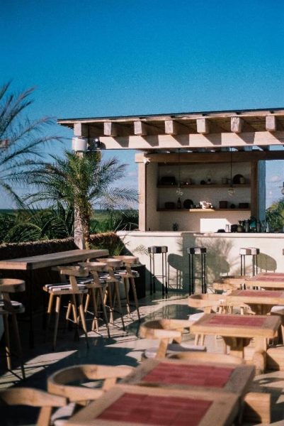 Terraza bar exterior con mesas de madera y zona de cócteles del Hotel Panamera rodeada de palmeras