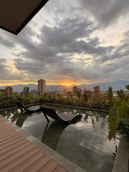 Piscina rooftop del Lettera Hotel con tumbonas y vistas panorámicas al atardecer sobre la ciudad