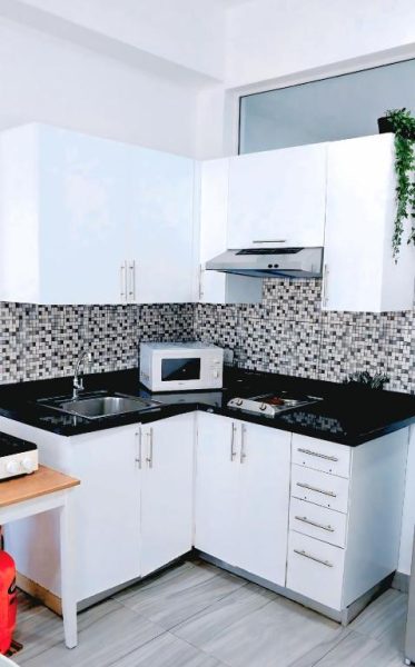 Cocina totalmente equipada con gabinetes blancos y encimera negra en Hotel Punta Cana Coral Beach Area I