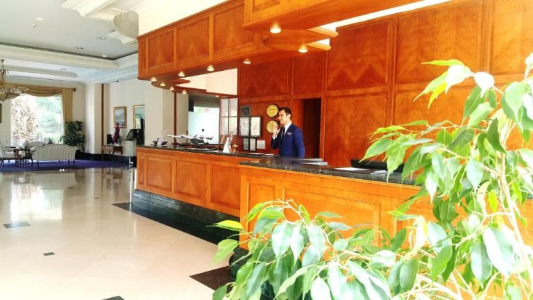 Recepción principal con mostrador de madera y personal atendiendo en IC Hotels Airport