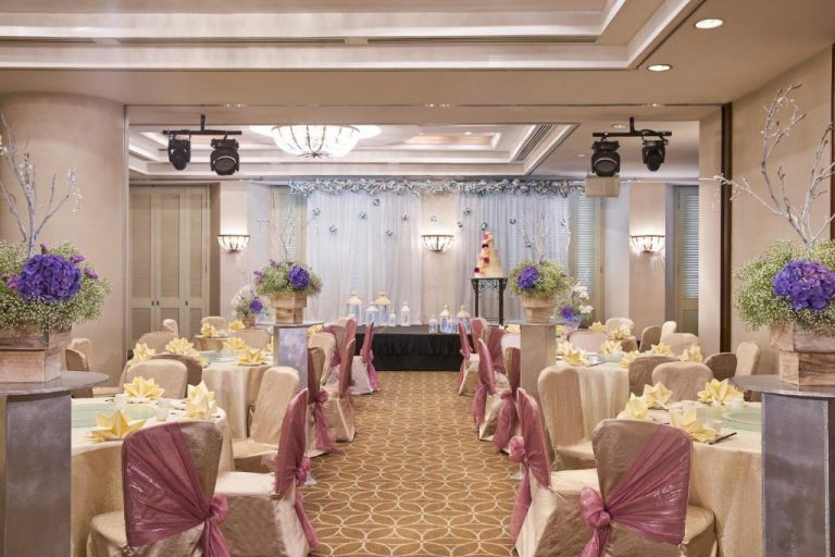 Salón de bodas elegante con decoración floral y mesas vestidas en Rendezvous Hotel Singapore