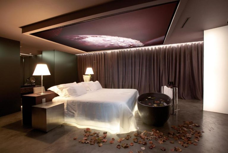 Suite de lujo con bañera exenta negra y cama doble con iluminación ambiental en The Vine Hotel