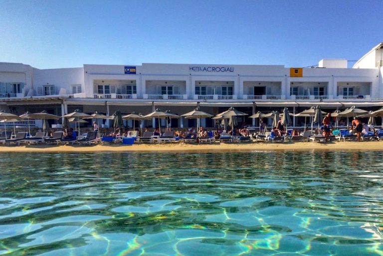 Vista desde el mar de la playa privada con tumbonas y sombrillas del Acrogiali Beachfront Hotel Mykonos