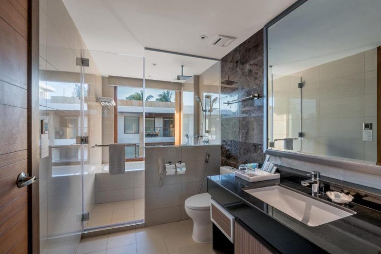 Baño moderno con ducha de lluvia y bañera en Henann Crystal Sands Resort con vista exterior