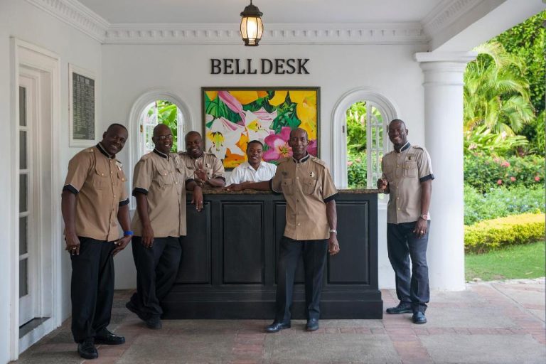 Equipo de conserjes en el Bell Desk del Hotel Half Moon Jamaica con uniforme beige