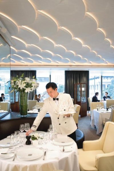 Camarero sirviendo en el elegante restaurante del Mandarin Oriental Hong Kong con decoración en blanco