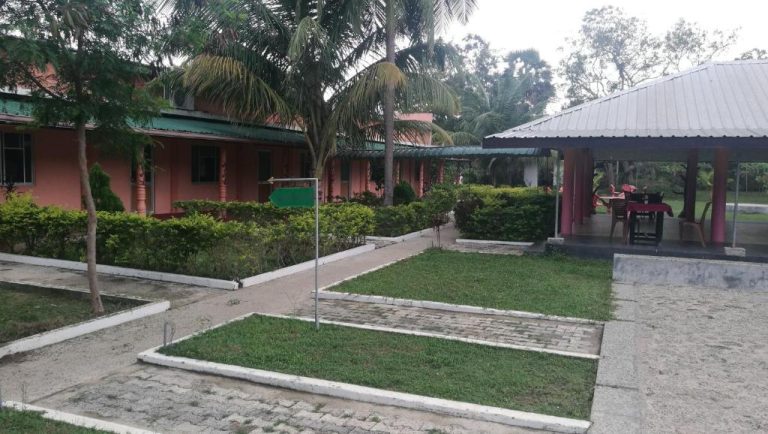 Jardín exterior con bungalows rosas y zona de comedor cubierta en Friends Paradise Resort
