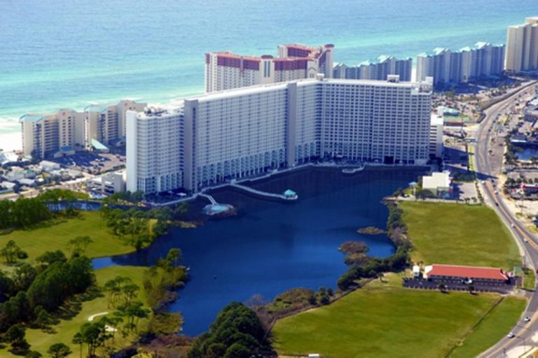 Vista aérea del Laketown Wharf Resort con lago, jardines verdes y playa del Golfo de México al fondo