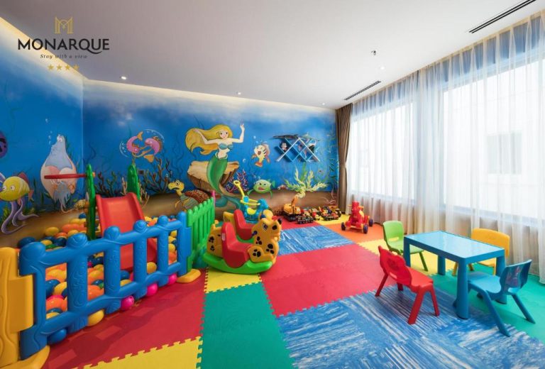 Sala de juegos infantil con tobogán, piscina de bolas y mural de sirenas en Monarque Hotel Danang