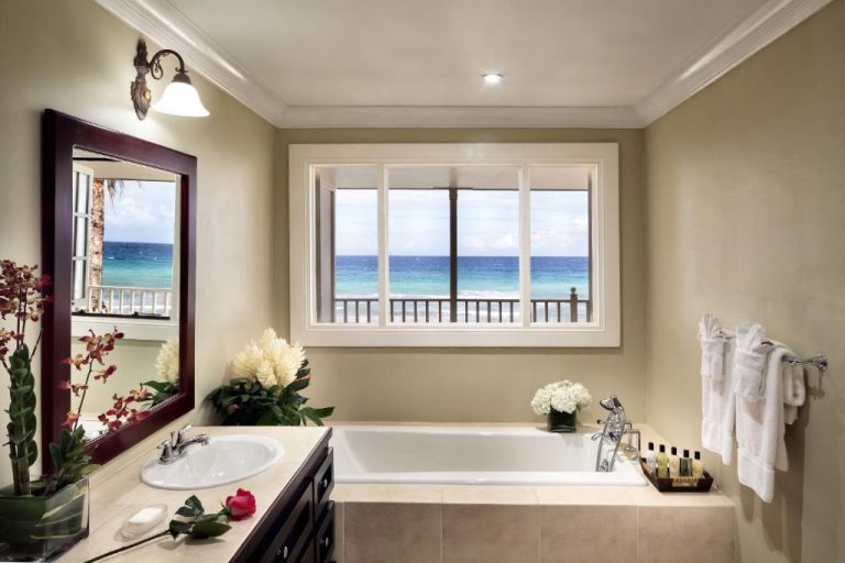 Lujoso baño con bañera y ventanal con vistas al mar turquesa en el Hotel Half Moon