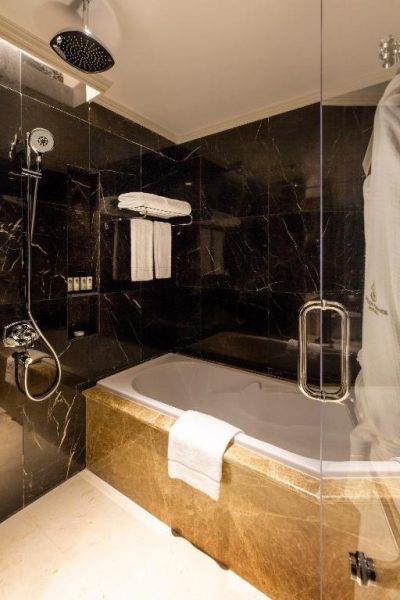 Lujoso baño con bañera empotrada y mármol negro en el Ezdan Palace Hotel de Qatar