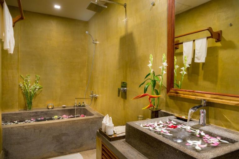 Baño de lujo con bañera de piedra y decoración floral en Khmer House Resort Cambodia