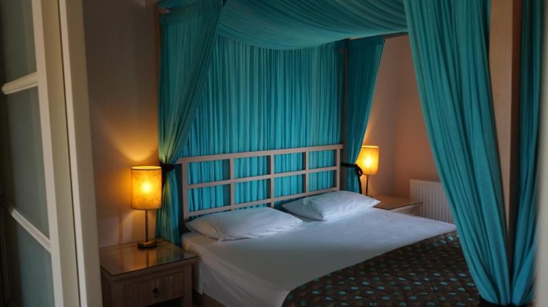 Habitación doble con cama de dosel y cortinas turquesas en Spiti Nikos