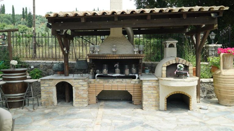 Cocina exterior con barbacoa y horno de leña de piedra en Spiti Nikos, ideal para asados
