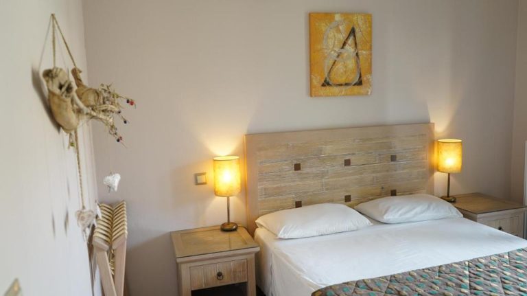 Habitación doble con cama matrimonial y mesitas de noche iluminadas en Spiti Nikos