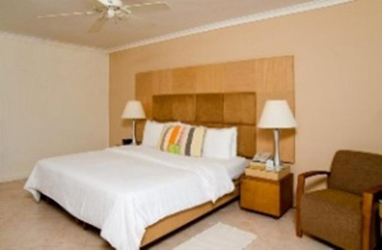 Habitación con cama king size y cabecero de madera en el hotel Mango Bay All Inclusive