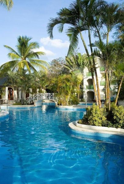 Piscina exterior rodeada de palmeras tropicales en el hotel Mango Bay All Inclusive Barbados
