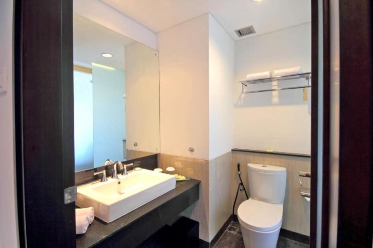 Baño moderno con lavabo, espejo y sanitario del Hotel Santika Siligita Nusa Dua en Bali