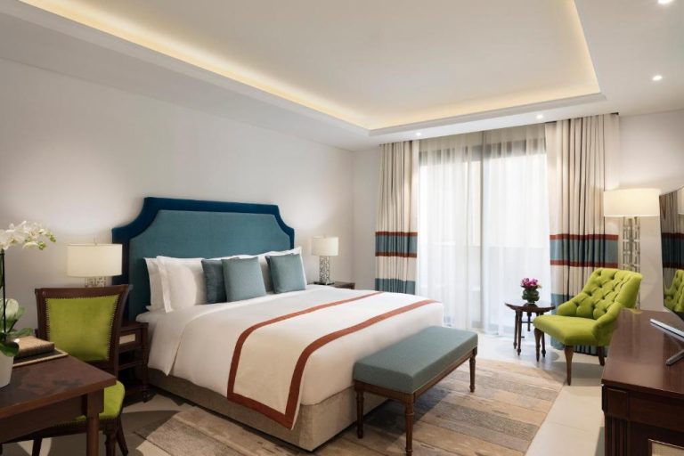 Habitación deluxe con cama king y cabecero azul en Al Najada Doha Hotel Apartments by Oaks