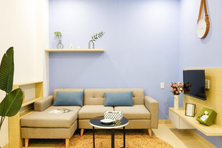 Salón moderno con sofá beige y cojines azules en Phuong Tran Apartment and Hotel