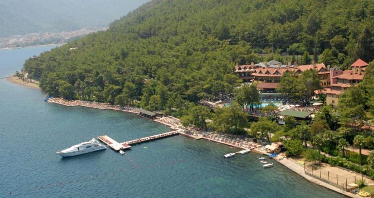 Vista aérea del Marmaris Park Hotel con playa privada, embarcadero y yate en la bahía de Marmaris
