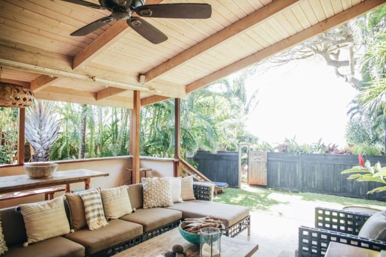 Terraza cubierta con sofás y jardín tropical del Paia Inn en Maui, Hawaii