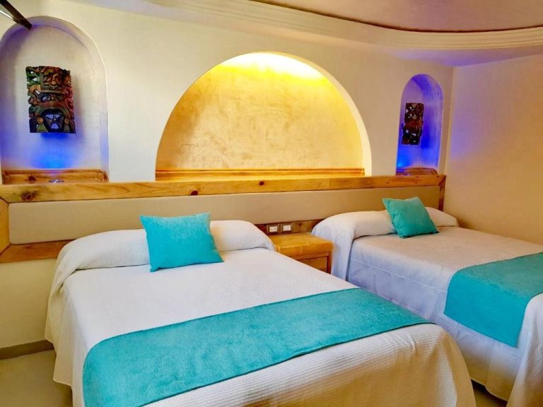 Habitación doble con decoración mexicana y camas con almohadas turquesa en Hotel Blue Star Cancun
