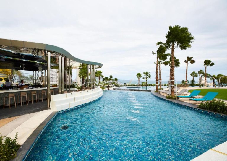 Piscina infinita con bar junto al mar del Grande Centre Point Pattaya con palmeras y tumbonas