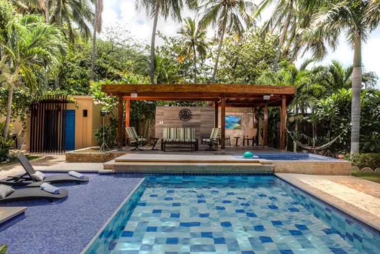 Piscina exterior con pérgola y zona lounge rodeada de palmeras en Casa Verano Beach Hotel Adults Only