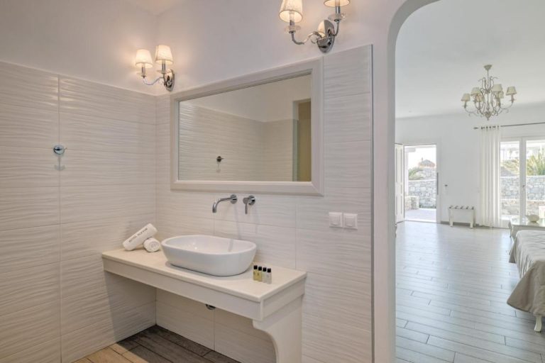 Baño blanco con lavabo de diseño y espejo del Hotel Alkyon con vistas a la habitación