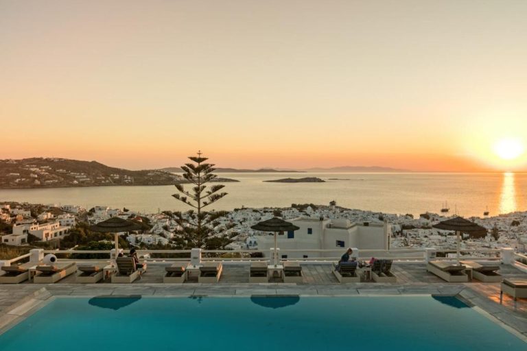Piscina infinita del Hotel Alkyon con vistas panorámicas al mar Egeo y la ciudad de Mykonos al atardecer