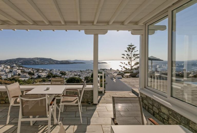 Terraza con comedor exterior y vistas panorámicas al mar y la ciudad blanca en Hotel Alkyon Mykonos
