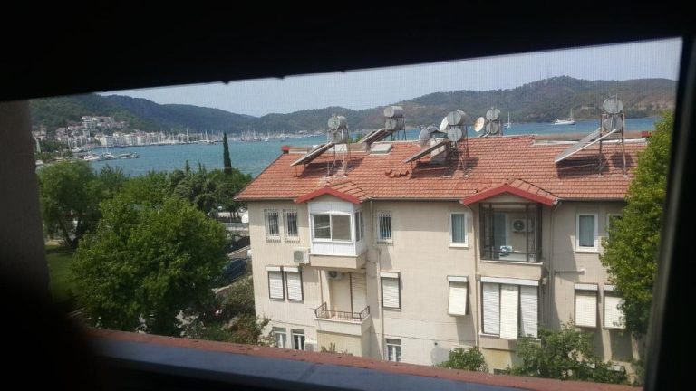 Vista desde ventana del Cicek Hotel Apartments con edificio, bahía y puerto deportivo al fondo