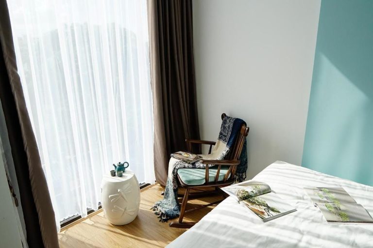 Habitación luminosa con sillón de madera y mesita de cerámica en Phuong Tran Apartment and Hotel