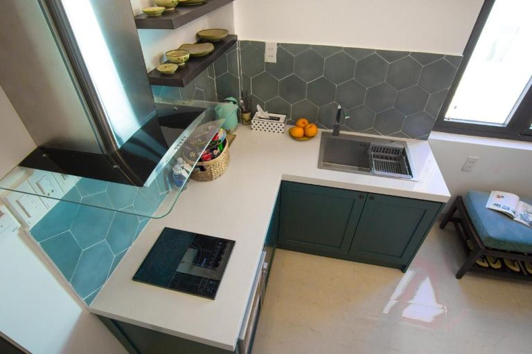 Cocina moderna completamente equipada con encimera blanca y gabinetes verdes en Phuong Tran Apartment and Hotel