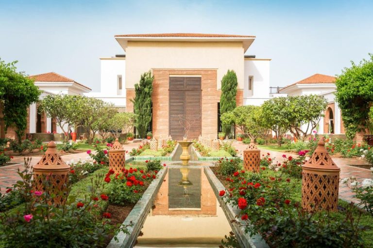 Jardín con fuente central y flores rojas en el hotel Robinson Agadir All Inclusive, Marruecos
