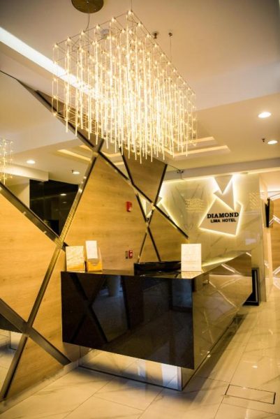 Recepción moderna con lámpara de araña dorada y diseño geométrico del Hotel Diamond Lima