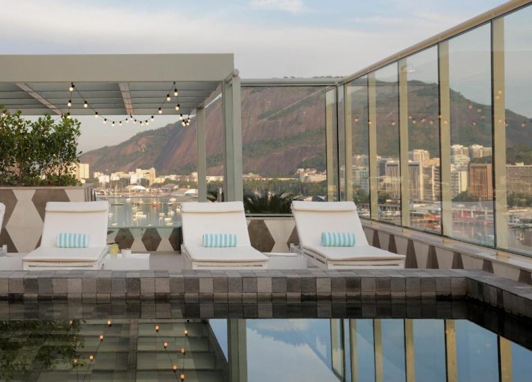 Terraza con piscina y tumbonas del Yoo2 Rio de Janeiro Hilton con vistas a la bahía y montañas