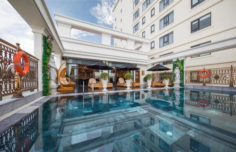 Piscina exterior con terraza y tumbonas del Monarque Hotel Danang con decoración clásica