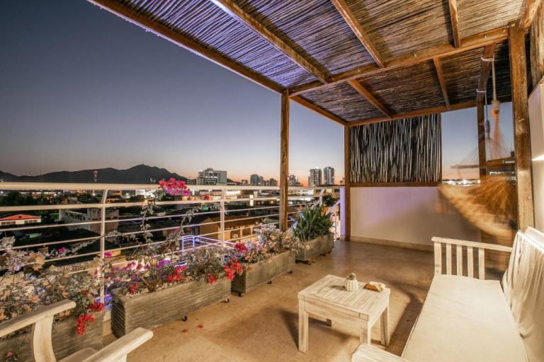 Terraza con pérgola de bambú y vistas panorámicas nocturnas de la ciudad en El Cactus Luxury Apartments