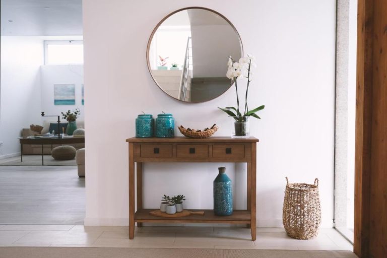 Recibidor elegante con consola de madera, espejo redondo y flores blancas en Sao Vicente Lodge Atlantic Retreat