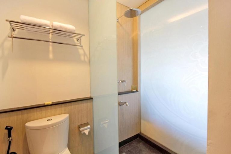 Baño moderno con ducha de lluvia y toilet en Hotel Santika Siligita Nusa Dua