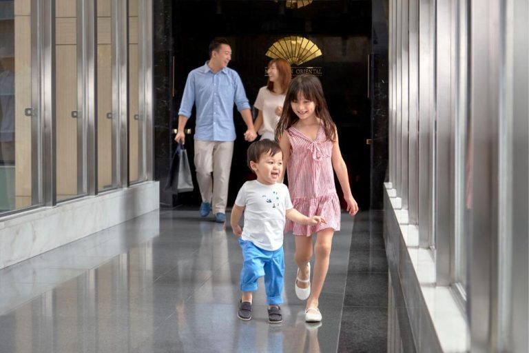 Familia con niños disfrutando de la entrada del Mandarin Oriental Hong Kong en un día de paseo